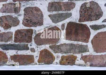 Mittelalterliche Steinwand-Hintergrundtextur im Winter. Stockfoto