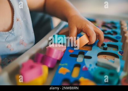 Nahaufnahme der Hände Ihres Babys, die in einem Puzzle aus bunten Figuren spielen. Bildungskonzept. Familienaktivitätskonzept. Ein glückliches Familien-Kind-Konzept Stockfoto