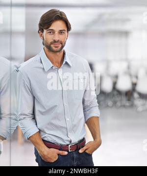 HES ein selbstbewusster junger Geschäftsmann. Porträt eines hübschen jungen Geschäftsmannes, der in seinem Büro steht. Stockfoto