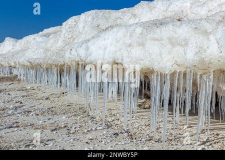 Nahaufnahme des eisigen Meeres, gefrorene Wellen, Felsen und Sonnenblendung auf dem Eis. Stockfoto