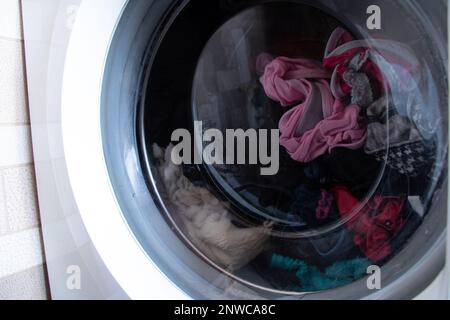 Dreckige alte Waschmaschine mit Sachen, Wäsche waschen in der Waschmaschine, waschen Stockfoto