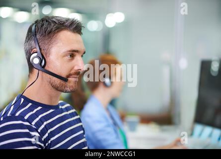 Professionelle Kundenbetreuung. Aufnahme eines jungen Geschäftsmanns, der ein Headset in einem Büro trägt. Stockfoto