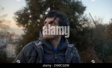 Attraktiver junger Mann, der in Gedanken verloren ist, während er in die Ferance im Herzen der Natur im Wald blickt Stockfoto