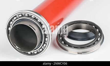 Einreihiges Kugellager aus Stahl in roter Metalldrucktrommel auf weißem Hintergrund. Rollelement auf Hohldruckwalze von Fixiereinheit des Laserdruckers. Stockfoto