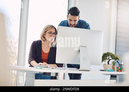 Kreatives Talent und Technologie für ein erfolgreiches Projekt kombinieren. Aufnahme eines jungen Mannes und einer jungen Frau, die in einem modernen Büro einen Computer benutzen. Stockfoto