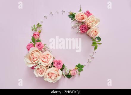 Rosafarbene Rosen und Blätter mit rundem Rahmen auf hellviolettem Blumenhintergrund. Stockfoto
