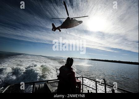 EIN US-AMERIKANISCHER Coast Guard Eurocopter MH-65 Dolphin Helicopter von Air Station Savannah schwebt während des Hubschraubertrainings im Hafen von Charleston, South Carolina, 5. Januar 2023. Die Besatzung trainiert routinemäßig für Hebevorrichtungen, falls eine medizinische Evakuierung in der Praxis erforderlich ist. Stockfoto