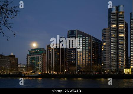 London, Großbritannien - 05. Februar 2023: Blick auf Apartments und moderne Gebäude am Albert Embankment in London über die Themse am Sommerabend mit Mondaufgang Stockfoto