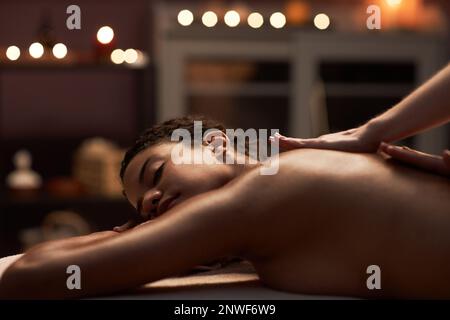 Junge Frau, die eine entspannende Rückenmassage im Spa-Salon genießt Stockfoto