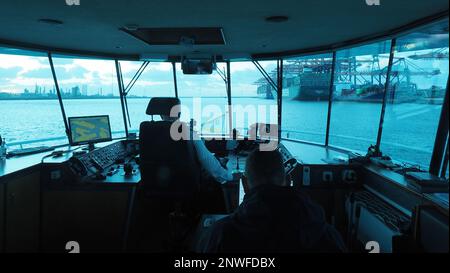 Blick von der Brücke eines kleineren Schiffs, das durch den Hochseehafen von Rotterdam segelt, einer der größten der Welt, mit zwei riesigen Containerschiffen Stockfoto