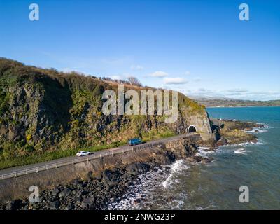 Luftaufnahmen von verschiedenen Orten in und um Larne, County Antrim, Nordirland. Auf diesem Foto ist dies die Küstenstraße A2 am Damm, die durch den schwarzen Arch-Tunnel führt, während Sie Larne weiter in Richtung Norden verlassen. Stockfoto