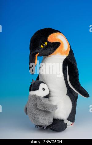 Ausgestopfte Tiere mit Kaiserpinguin für Erwachsene und Babys auf einem nahtlosen blau-weißen Hintergrund. Stockfoto