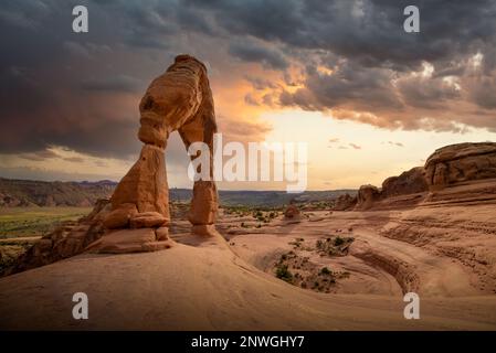 Kultiger Delicate Arch bei Sonnenuntergang mit stürmischem Himmelshintergrund. Stockfoto