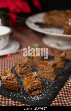 Nahaufnahme einiger Papaya-Kuchenscheiben auf einem dekorierten Tisch mit einigen Kaffeetassen und dem Rest des Kuchens im Hintergrund Stockfoto