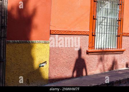 San Miguel de Allende Guanajuato Mexico, historisches Zentrum des historischen Stadtzentrums, menschliche Schattensilhouette, farbenfrohe orangefarbene Mauer, Gebäude, Stadt Stockfoto