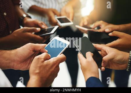 Die erfolgreiche Teambindung aufrecht erhalten. Nahaufnahme einer Gruppe von nicht erkennbaren Geschäftsleuten, die ihre Mobiltelefone synchron benutzen. Stockfoto
