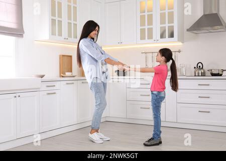 Glückliche Mutter und Tochter tanzen zusammen in der Küche. Alleinerziehende Eltern Stockfoto