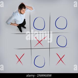 Mann und Darstellung des Tic-tac-Toe-Spiels auf grauem Hintergrund, über der Ansicht. Konzept der Geschäftsstrategie Stockfoto