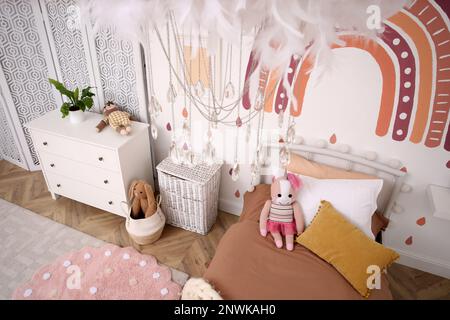 Stilvolles Zimmer mit komfortablem Bett für Kinder, Blick über die Kulisse. Innendesign Stockfoto