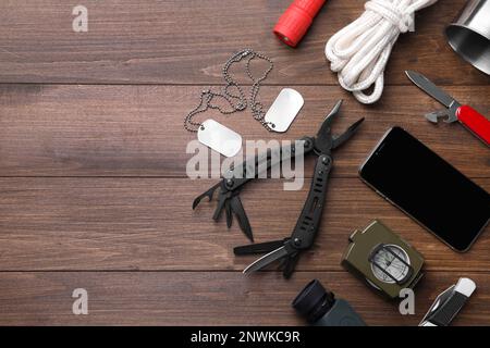 Flache Verlegung mit kompaktem tragbarem Multitool und Zubehör auf Holzhintergrund. Platz für Text Stockfoto