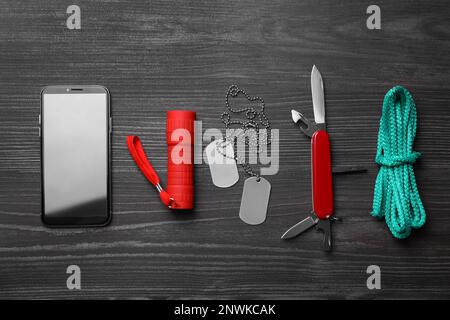 Flache Verlegung mit kompaktem tragbarem Multitool und Zubehör auf schwarzem Holztisch Stockfoto