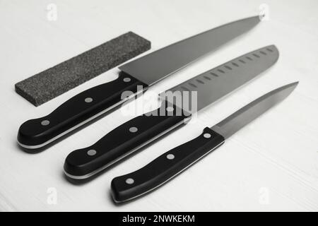 Schleifstein und Messersatz auf weißem Holztisch Stockfoto
