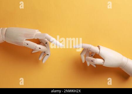 Hände von Schaufensterpuppen aus Holz auf orangefarbenem Hintergrund, flach liegend Stockfoto