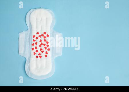 Menstruationspad mit Konfetti auf hellblauem Hintergrund, Draufsicht. Platz für Text Stockfoto