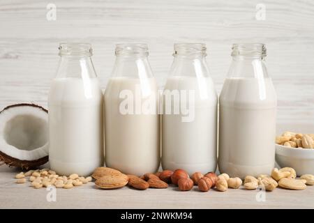 Verschiedene Nussmilch in Glasflaschen auf weißem Tisch Stockfoto