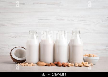 Verschiedene Nussmilch in Glasflaschen auf weißem Tisch Stockfoto