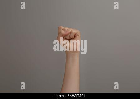 Frau hebt Faust auf grauem Hintergrund, Nahaufnahme Stockfoto