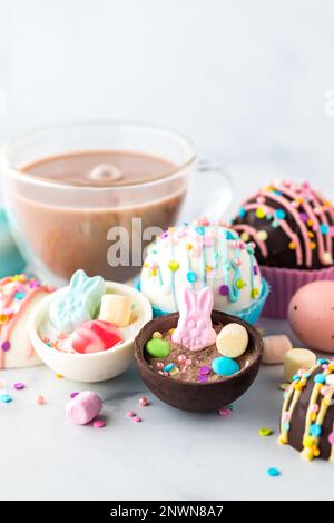 Heiße Schokoladenbomben, dekoriert für Ostern mit einer Glas heißen Kakao dahinter Stockfoto