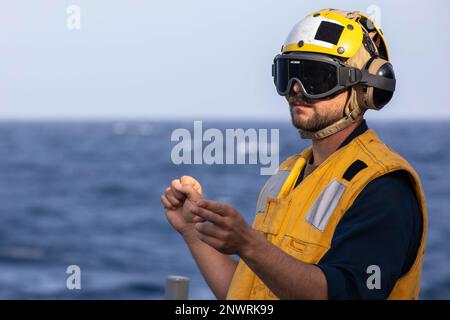 230118-N-SN516-1022 SÜDCHINESISCHES MEER (18. JANUAR 2023) USA Navy Boatswain's Mate 3. Class Keaton Lester aus Wichita Falls, Texas, sendet Handsignale an die Cockpit-Crew während der Flugquartiere an Bord der Arleigh-Burke-Klasse-Guided-Missile Destroyer USS Decatur (DDG 73). Decatur, Teil der Nimitz Carrier Strike Group, gehört zur US-7.-Flotte und führt Routinevorgänge durch. 7. Fleet sind die USA Die größte Flotte der Navy, die mit einer Anzahl von Flotten ausgestattet ist, arbeitet regelmäßig mit Alliierten und Partnern zusammen, um eine freie und offene Region Indopazifik zu erhalten. Stockfoto