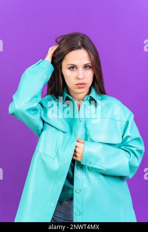 Nahaufnahme eines jungen Weißen in blauem Trenchcoat isoliert auf lila Hintergrund, der in die Kamera schaut Stockfoto