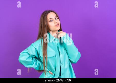 Nahaufnahme eines jungen Weißen im blauen Trenchcoat, isoliert auf lila Hintergrund, lächelnd Stockfoto