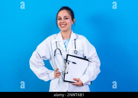 Porträt einer lächelnden Ärztin im Arztkleid isoliert auf blau, medizinisches Konzept Stockfoto