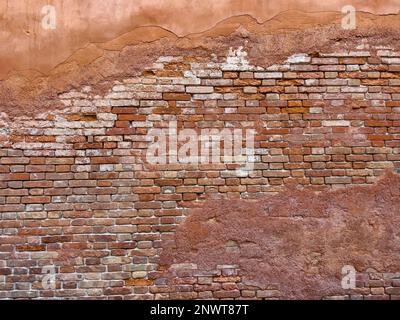 Hellbraune Malerreste an der Ziegelwand eines alten Gebäudes. Wandhintergrund im Design-Loft-Stil. Grunge rötlich-braun, mit Kopierbereich. Stockfoto