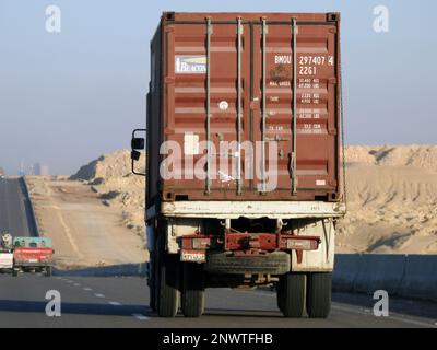 Gizeh, Ägypten, Januar 26 2023: Großer Tieflader-Lkw mit einem Stahlcontainer auf einer Autobahn in Ägypten, Versand- und Lieferservice-con Stockfoto