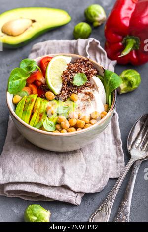 Schüssel mit gesundem Salat. Schüssel mit einer Mischung aus Kichererbse, Avocado, Huhn, Quinoasamen, rotem Paprika, Frischer Spinat, Limette. Saubere, gesunde Ernährung Stockfoto