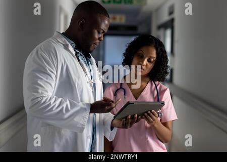 Verschiedene männliche und weibliche Ärzte mit Stethoskopen, die Tabletten im Krankenhaus verwenden. Gesundheits-, Krankenhaus- und Pflegekonzept. Stockfoto