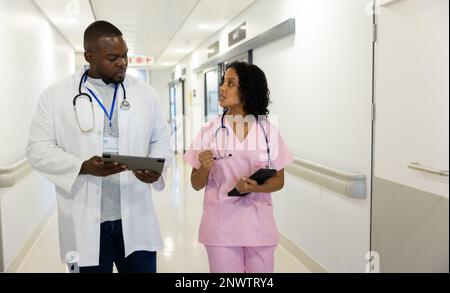 Verschiedene männliche und weibliche Ärzte mit Stethoskopen, die Tabletten im Krankenhaus verwenden. Gesundheits-, Krankenhaus- und Pflegekonzept. Stockfoto