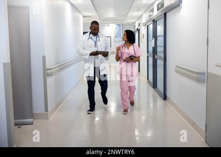 Verschiedene männliche und weibliche Ärzte mit Stethoskopen, die Tabletten im Krankenhaus verwenden. Gesundheits-, Krankenhaus- und Pflegekonzept. Stockfoto