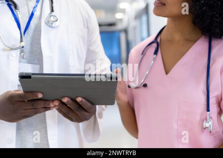 Verschiedene männliche und weibliche Ärzte mit Stethoskopen, die Tabletten im Krankenhaus verwenden. Gesundheits-, Krankenhaus- und Pflegekonzept. Stockfoto