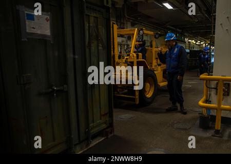 230203-N-VO895-1092 ATLANTISCHER OZEAN (3. Februar 2023) Boatswain's Mate 2. Class David Boatright, ein Matrose an Bord des Amphibienschiffs USS Bataan der Wasp-Klasse (LHD 5), führt einen Gabelstaplerfahrer während des Bohrdeckbetriebs zu einem Container, 3. Februar 2023. Die USS Bataan, das Amphibiengeschwader 8 (PHIBRON) und die 26. Marineexpeditionseinheit (26. MEU), die alle Teil der Bataan Amphibious Readiness Group (BATARG) sind, nehmen derzeit an einer PHIBRON-MEU-Übung zur integrierten Ausbildung (PMINT) Teil. Stockfoto