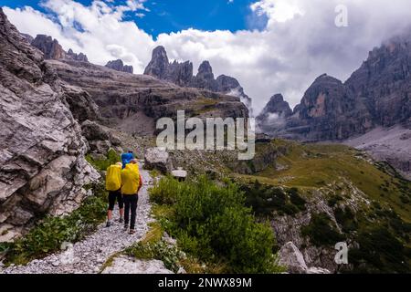 Drei Wanderer gehen auf einem Pfad zur Berghütte Rifugio Maria e Alberto al Brentei in Val Brenta in den Dolomiten von Brenta. Stockfoto