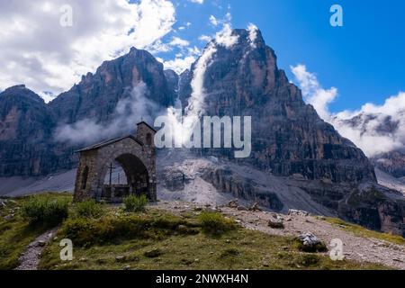 Die kleine Kapelle in der Nähe der Berghütte Rifugio Maria e Alberto al Brentei in Brenta Dolomiten, Gipfel des Crozzon di Brenta in der Ferne. Stockfoto