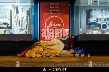 München, Deutschland. 01. März 2023. Ein Obdachloser schläft im Licht eines Schaufensters in der Innenstadt bei Temperaturen unter dem Gefrierpunkt. Kredit: Peter Kneffel/dpa/Alamy Live News Stockfoto