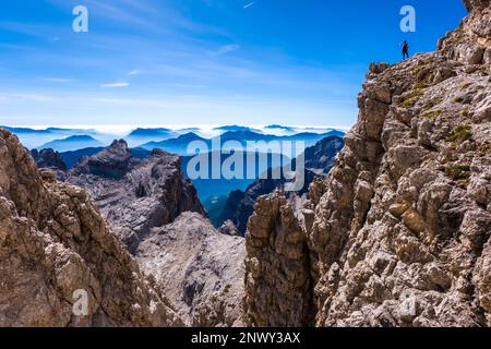 Ein Kletterer beobachtet die Silhouetten von Tälern und Bergen östlich der wichtigsten Dolomiten von Brenta, die von der Via ferrata Via delle Bocchette aus gesehen werden. Stockfoto