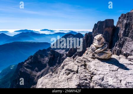 Eine Felskirche, die die Via ferrata Via delle Bocchette markiert, Silhouetten von Tälern und Bergen östlich der Hauptkette der Brenta-Dolomiten in der Dista Stockfoto