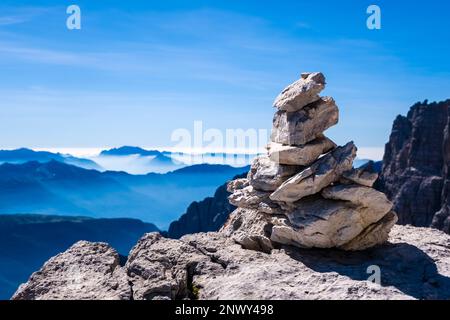 Eine Felskirche, die die Via ferrata Via delle Bocchette markiert, Silhouetten von Tälern und Bergen östlich der Hauptkette der Brenta-Dolomiten in der Dista Stockfoto